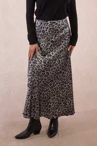 Person wearing a leopard print skirt with a plain background